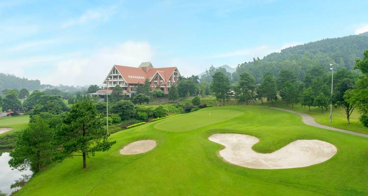 Een golfbaan met een clubhuis gelegen in een bosrijk gebied.