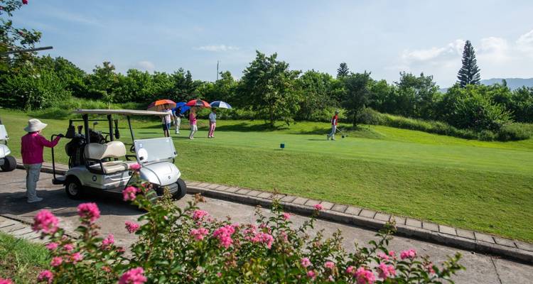 Golfbaan met golfkarretjes en mensen die spelen.