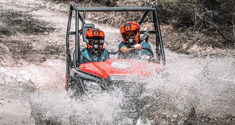 ATV, das durch Wasser auf einem unbefestigten Weg spritzt.