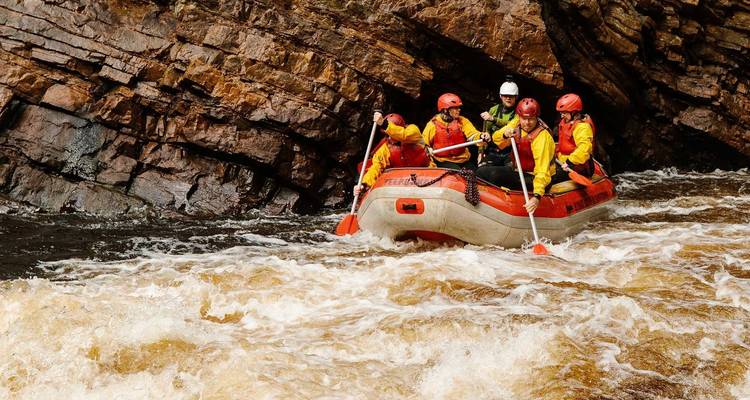 Gruppe von Raftingfahrern, die durch Stromschnellen in einer Schlucht navigiert.