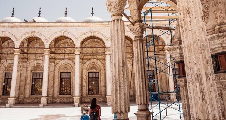 Binnenplaats van een historisch gebouw met een persoon die loopt en wat bouwsteigers.