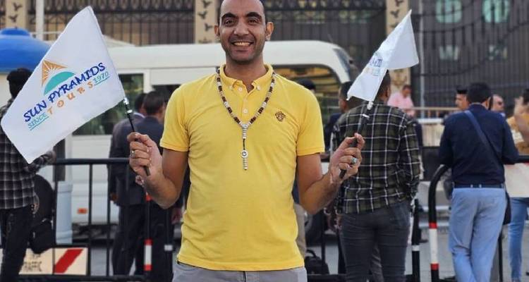 Een glimlachende man met vlaggen voor een cruiseschip.