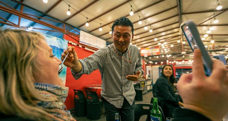 Serveur servant un client dans un marché animé