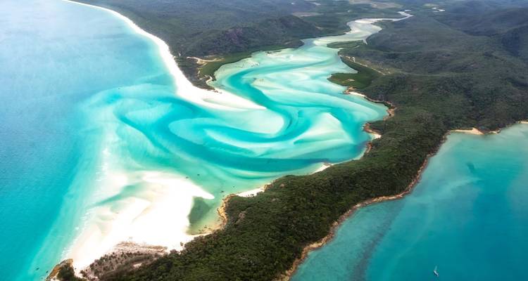 Luftaufnahme von wunderschönen türkisfarbenen und weißen wirbelnden Sandformationen und blauem Wasser entlang einer Küstenlinie.