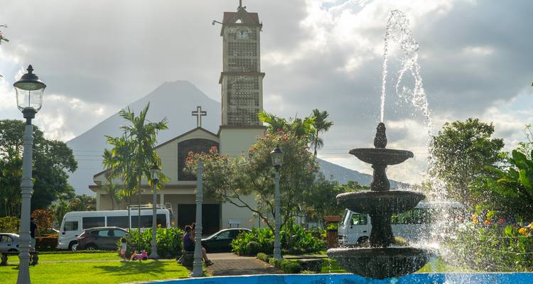 Brunnen und Kirche mit einem Vulkanberg im Hintergrund.