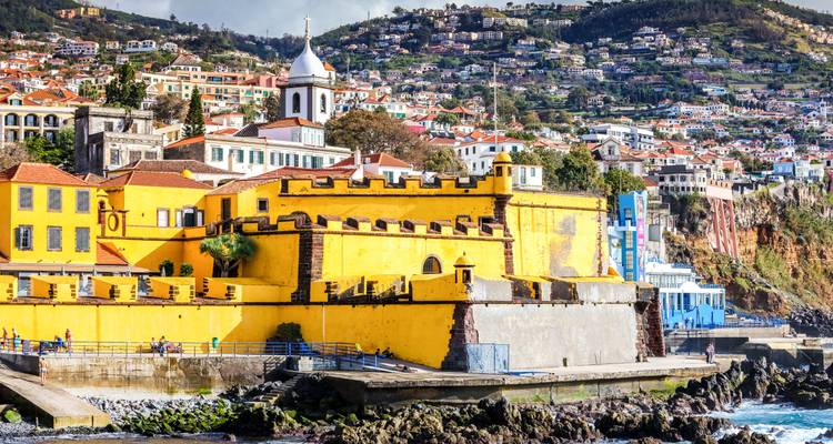Ville côtière colorée avec fort jaune et toile de fond océanique.
