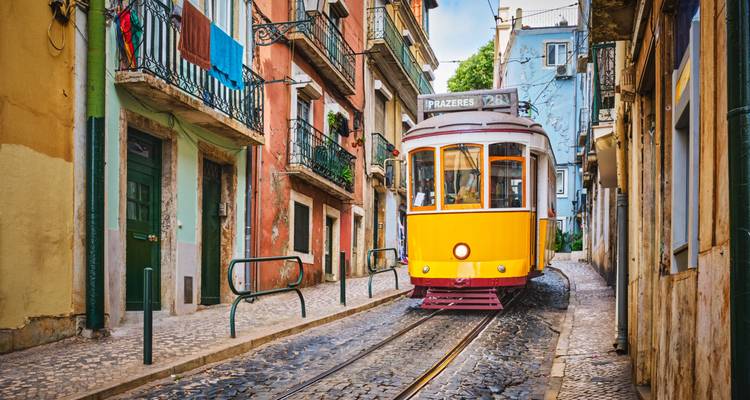 Un tramway dans une rue étroite entre des bâtiments colorés.