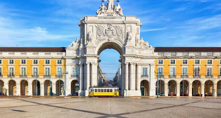 Une place avec une arche ornée et un tramway passant en dessous.