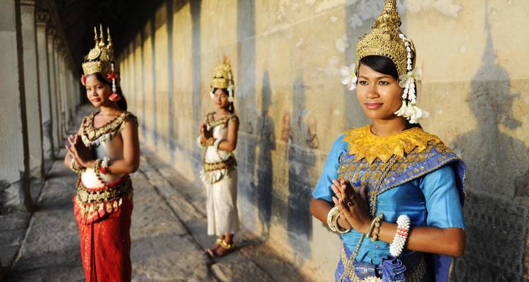 Drie vrouwen in traditionele kostuums die poseren tegen een muur