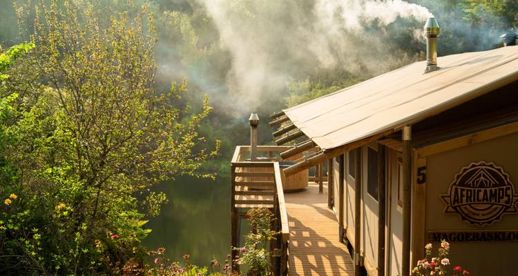 Cabane avec de la fumée qui s'élève dans une zone boisée.