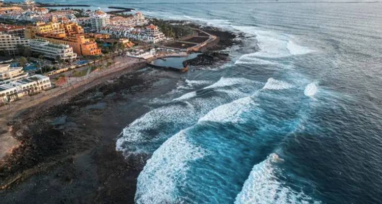 Vue aérienne d'une ville côtière avec des vagues qui se brisent sur le rivage.
