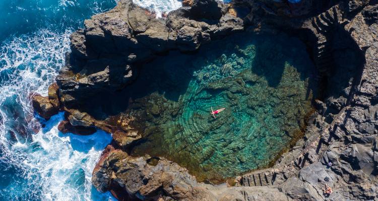 Vue aérienne d'une piscine naturelle avec une personne qui flotte.