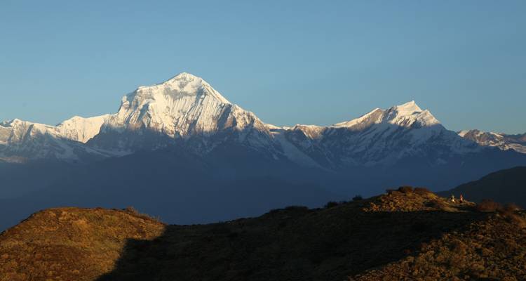 Besneeuwde bergketen onder een strakblauwe hemel.