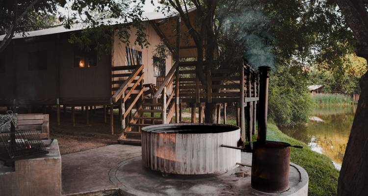 Cozy camp setting with a fire pit and wooden house.