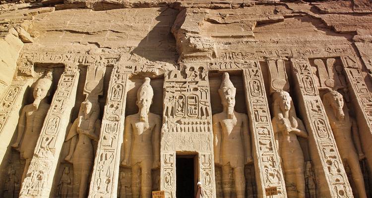 Ancient Egyptian temple facade with statues and hieroglyphs.