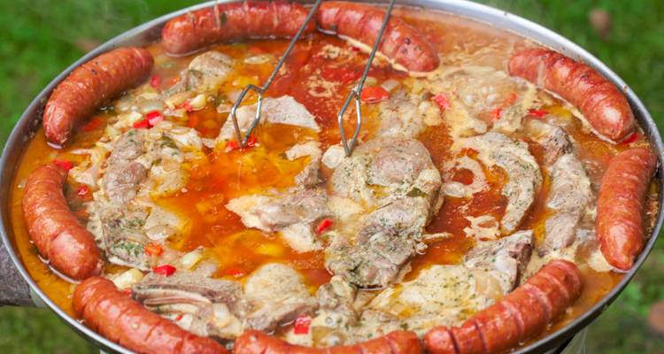 Olla llena de varias carnes cocinando al aire libre