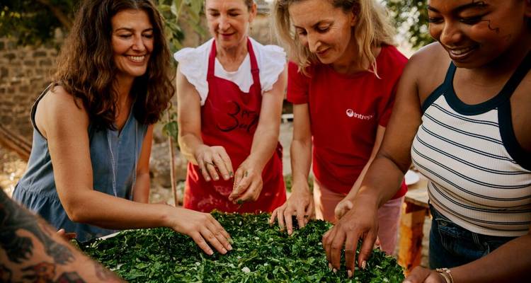 Personas preparando un plato grande con verduras.