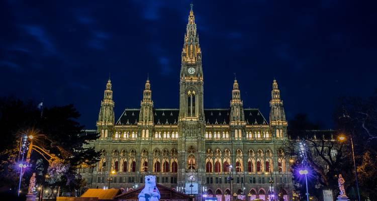 Illuminated neo-gothic city hall building beautifully lit against a deep blue night sky.
