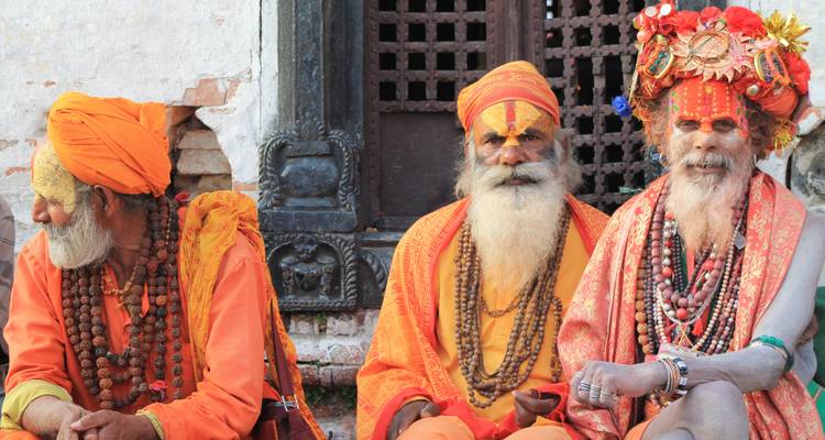 Three men dressed in vibrant traditional clothing sitting together.