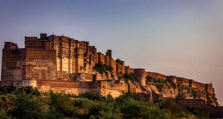 Massive historic fortification on a hill during sunset.