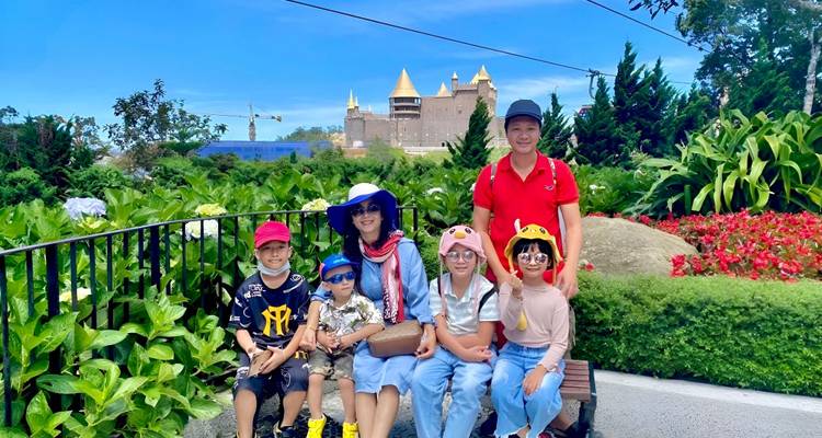 Famille posant pour une photo dans un jardin de fleurs avec un château en arrière-plan.