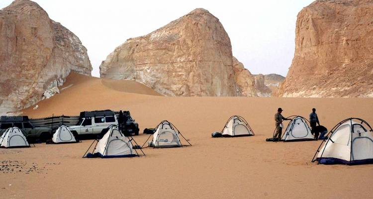 Tentes de camping dans le Désert Blanc avec un arrière-plan rocheux.
