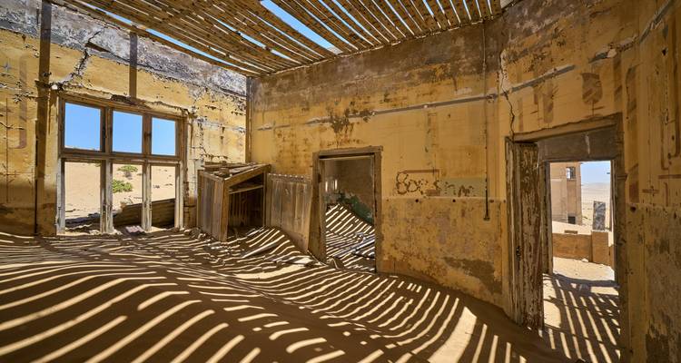 Interior de edificio abandonado lleno de dunas de arena.