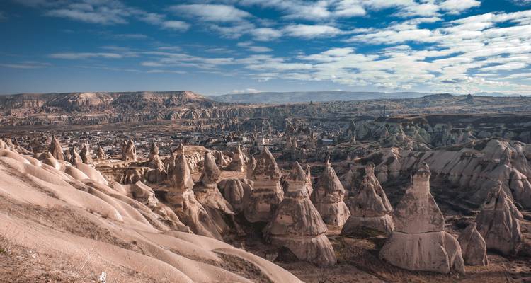 A landscape of unique rock formations under a sky with scattered clouds.