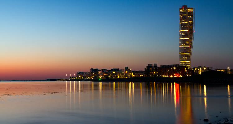El rascacielos Turning Torso y los reflejos del atardecer en el agua tranquila al anochecer en Malmö.