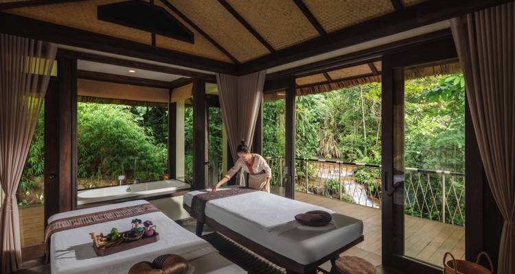 Een persoon die een massagetafel klaarmaakt in een rustige kamer met uitzicht op het bos.