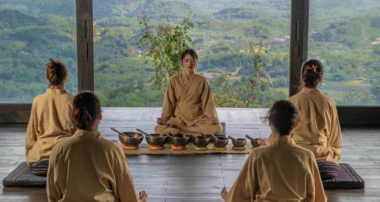 Een groep die deelneemt aan een serene meditatiesessie met uitzicht op een schilderachtig landschap.