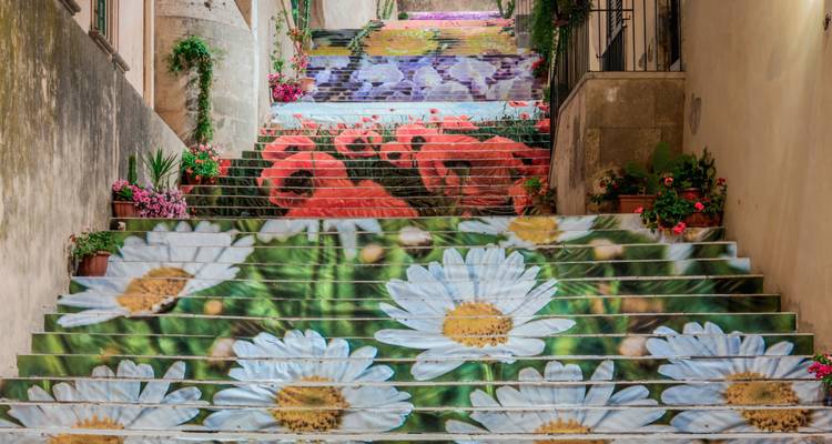 Escalera decorativa cubierta con arte floral gigante y plantas en macetas alineadas en los escalones.