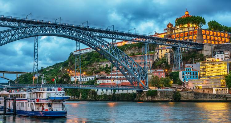 Puente Dom Luís I iluminado al atardecer atravesando el río Douro en Oporto.