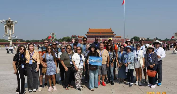 Gruppe von Touristen auf dem Tiananmen-Platz in Peking mit der Verbotenen Stadt im Hintergrund.