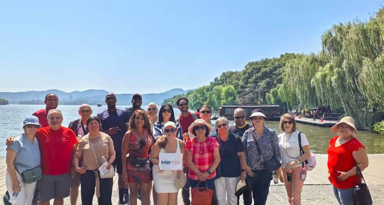 Touristen an einem Seeufer mit malerischem Blick auf Berge und Grün.