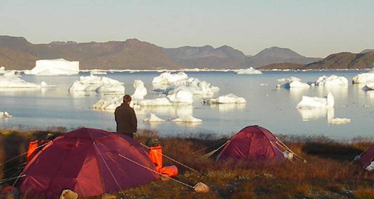 Campsite with tents near an icy waterfront landscape.