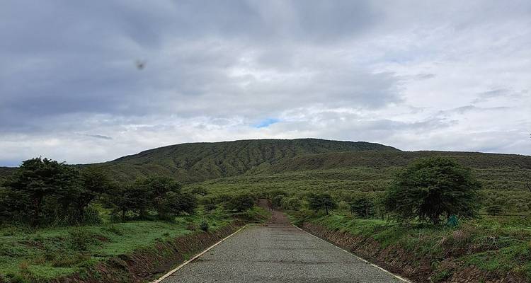 Straße, die zu einem grünen Berg unter einem bewölkten Himmel führt.