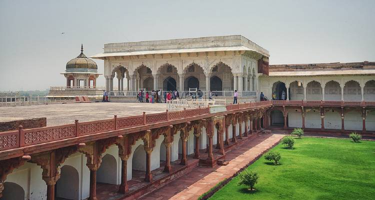 Ein verzierter Pavillon aus weißem Marmor und rote Sandsteinbögen überblicken gepflegte Rasenflächen innerhalb des Agra Fort.