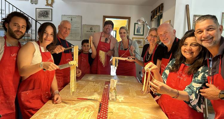 Group making pasta in a kitchen wearing aprons