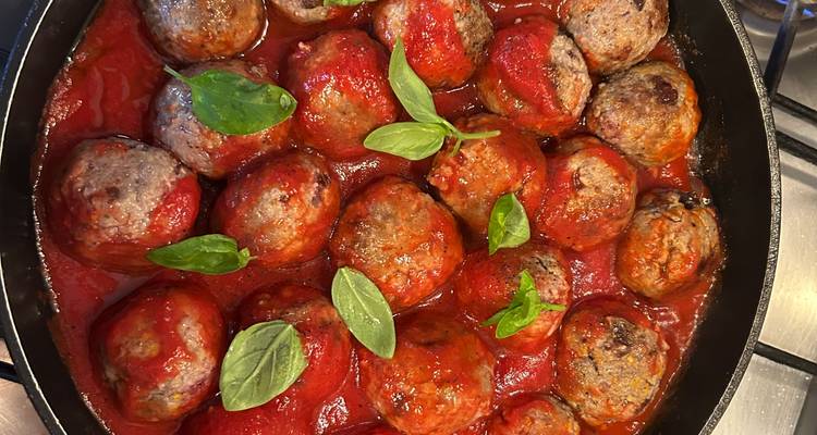 Meatballs simmering in tomato sauce with basil