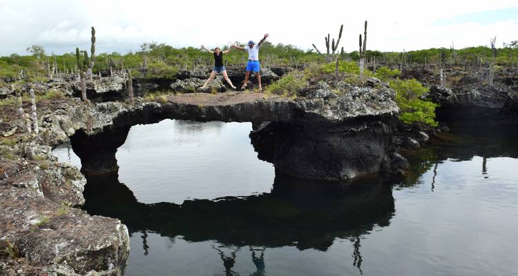 Zwei Menschen springen auf einer natürlichen Brücke über dem Wasser.