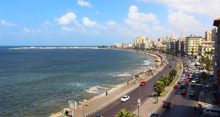 Vue panoramique de la Corniche d'Alexandrie avec une route côtière animée qui serpente le long de la Méditerranée.