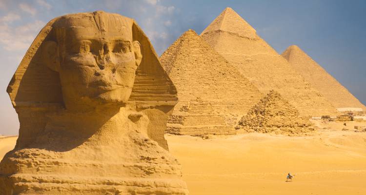 Sphinx emblématique au premier plan avec les trois grandes pyramides qui s'élèvent derrière contre un ciel brumeux.