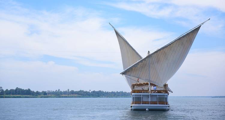 Vue arrière d'une felouque aux voiles larges capturant le vent sur les eaux ouvertes du Nil.