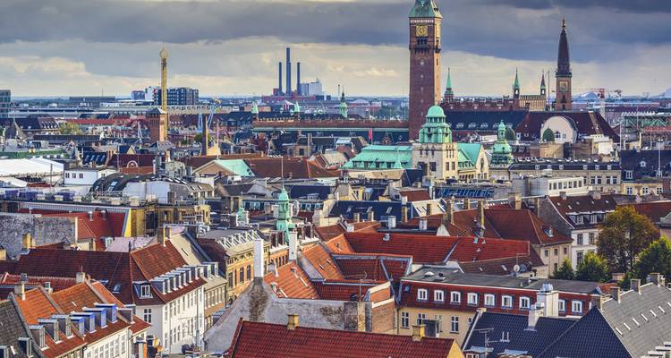 Panoramic view of Copenhagen's skyline with mixed architectural styles and cloudy sky.