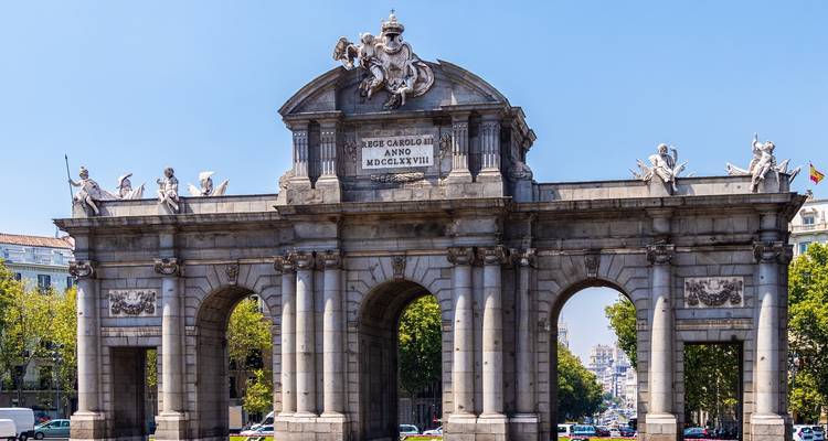Puerta de piedra histórica con varios arcos en un entorno urbano.