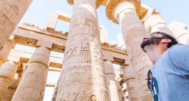 Hombre mirando columnas antiguas con jeroglíficos grabados.