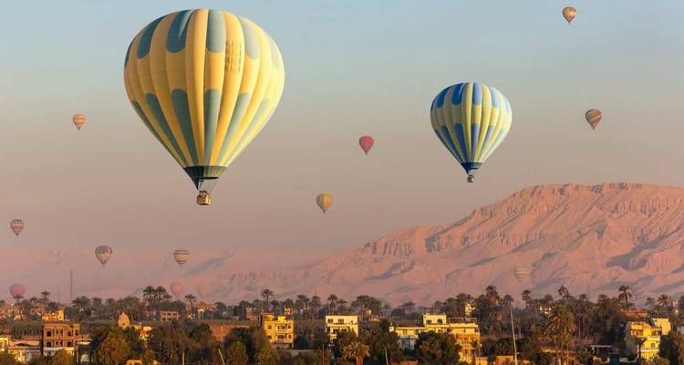 Globos aerostáticos volando sobre un paisaje egipcio.