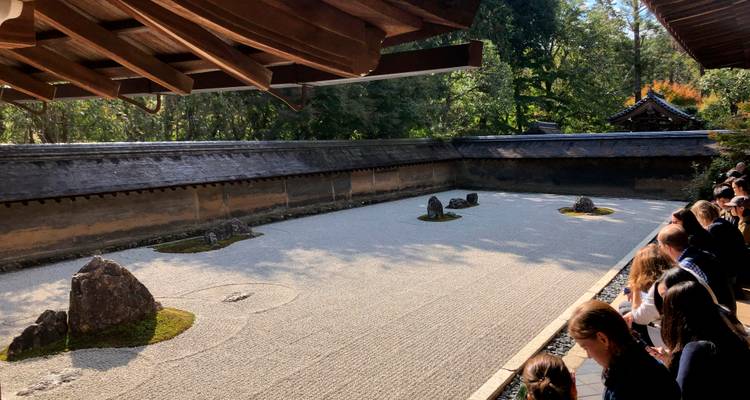 Los visitantes ven el famoso jardín de rocas Zen del Templo Ryoan-ji desde una veranda de madera.