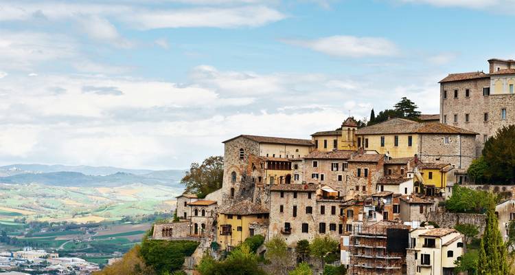 Stone hilltop village perched above verdant valleys with sweeping countryside views.